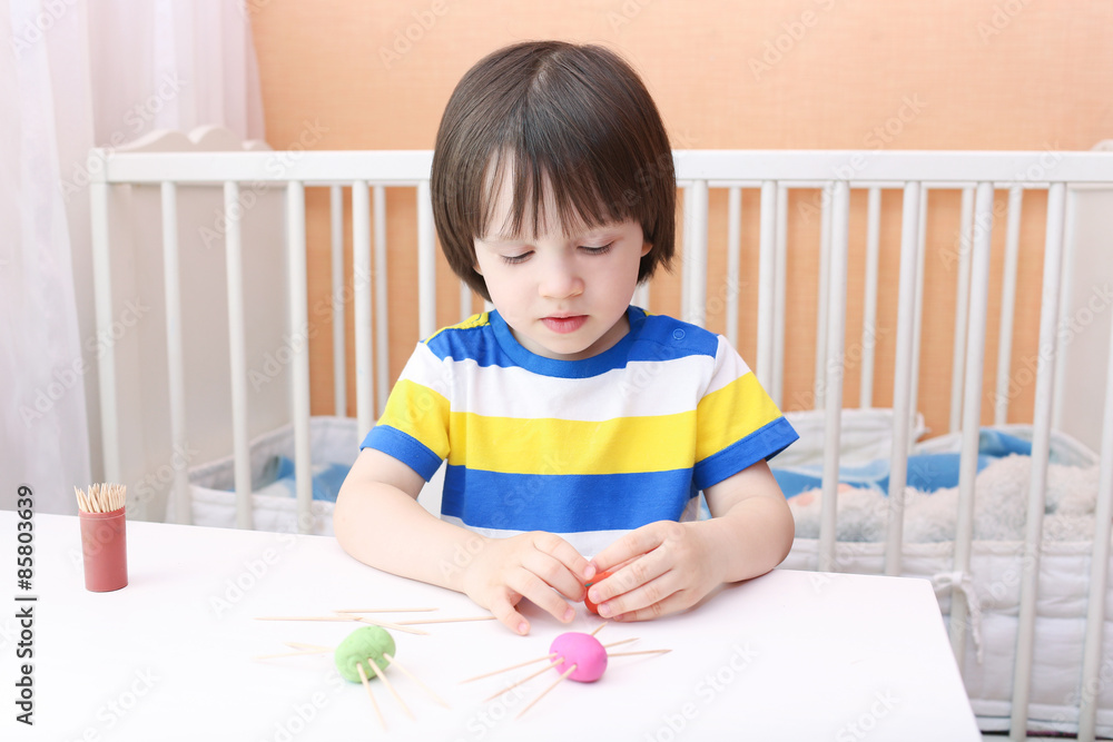 Portrait of cute little child making toothpick legs by playdough Portrait of cute little child making toothpick legs by playdough
