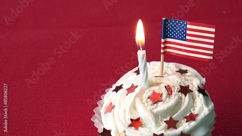 Birthday cupcake decorated with red stars and american flag with red background.  Flag is blown out.