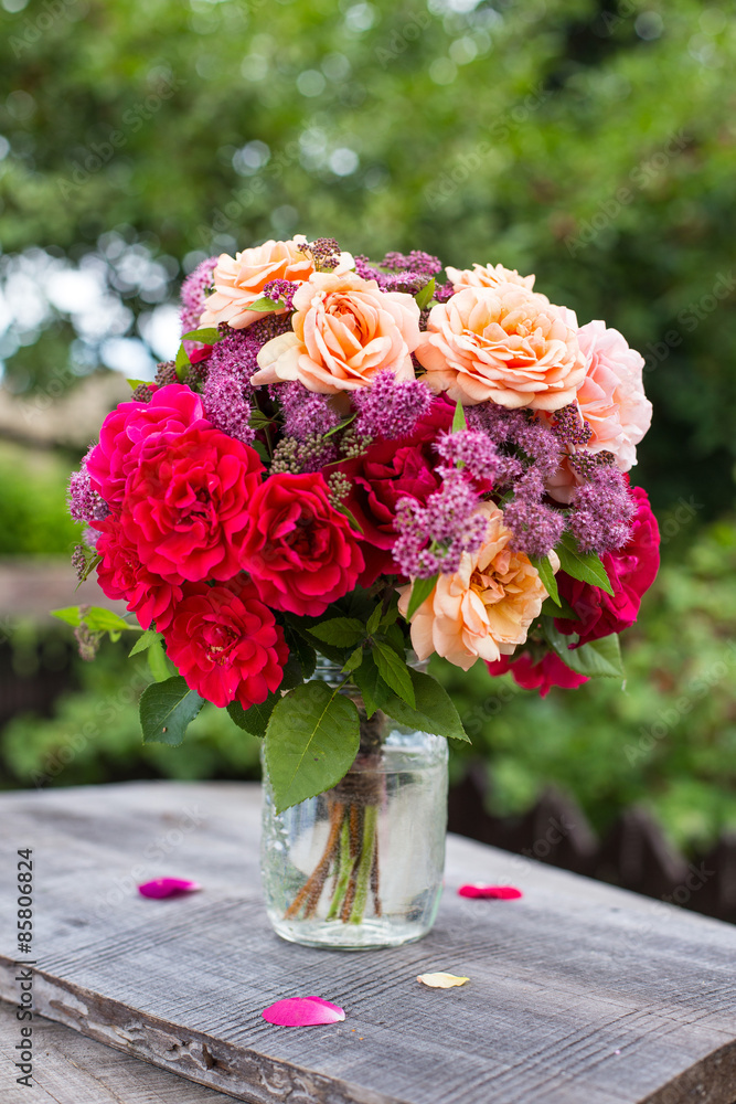 Fototapeta premium Bouquet of pink and apricot garden roses on wooden table