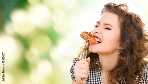 Bild auf Leinwand hungry young woman eating meat on fork over green