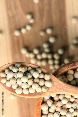 white pepper seeds on wooden background.