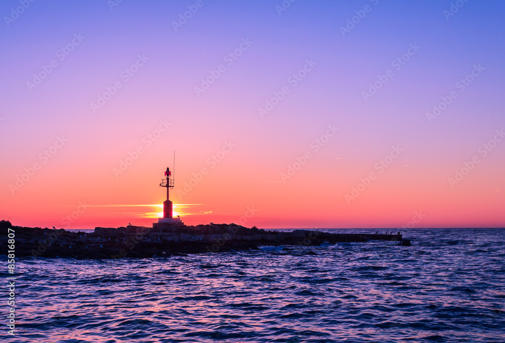 Scenic view of beautiful sunset above the sea with silhouette of island and light house