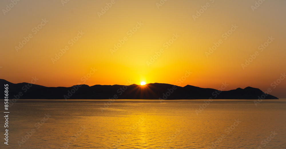 Scenic view of beautiful sunset above the sea with silhouette of island