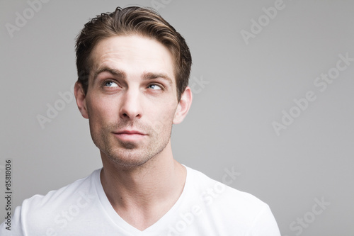 Thoughtful sly guy in white t-shirt