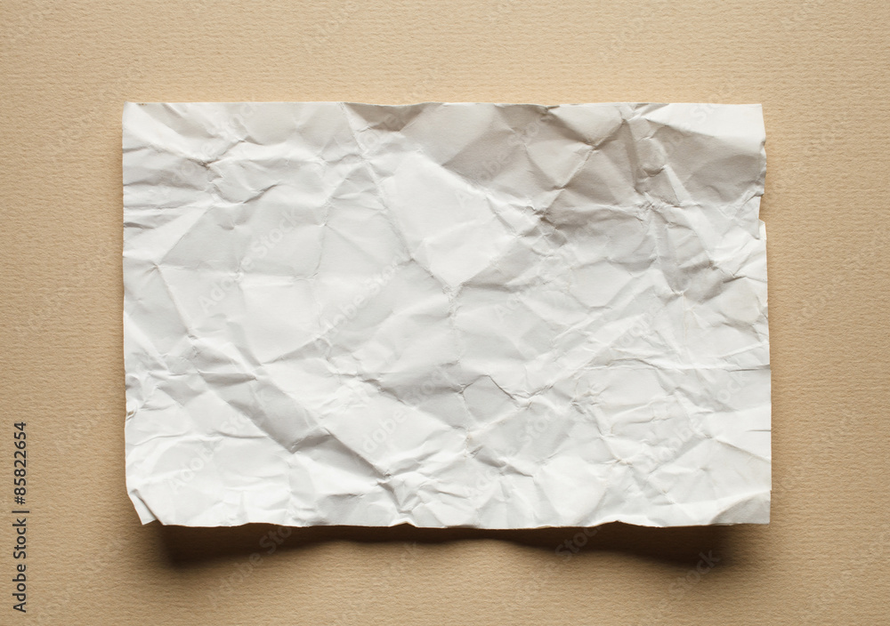 Obraz premium Crumpled white paper card on beige background, place for text