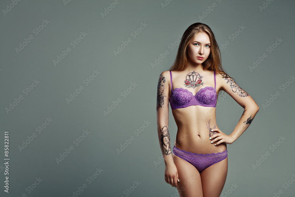 Naklejka premium pretty girl with much tattoo in purple lingerie