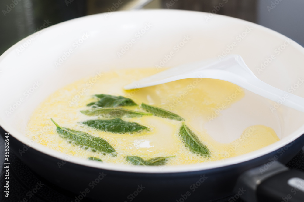 Closeup of Fresh Sage Leaves Being Fried with Butter in a Ceramic Pan Closeup of Fresh Sage Leaves Being Fried with Butter in a Ceramic Pan