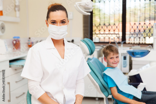 female dentist in office with child patient in background