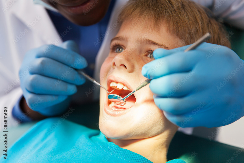 african male dentist examining little boy teeth african male dentist examining little boy teeth