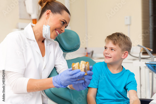 female dentist explaining teeth model to little patient