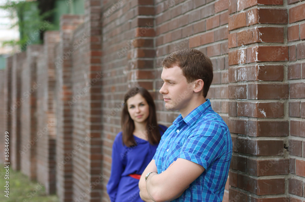 Man stands near brick wall at summer day and woman stands Man stands near brick wall at summer day and woman stands