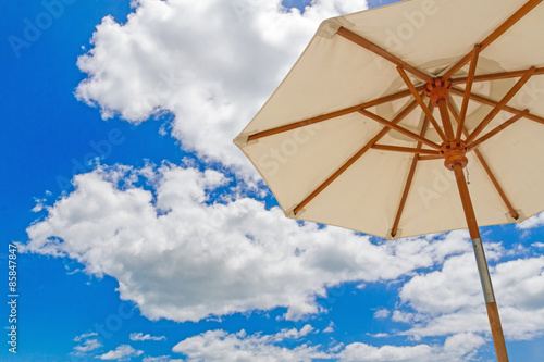 Beach umbella on blue sky with clouds 