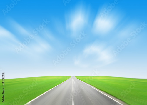 Asphalt road through the green field and blue sky