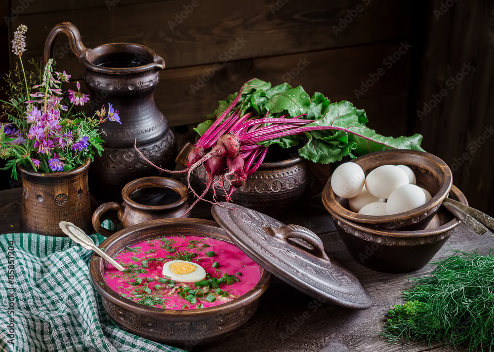 Russian cold soup with beetroot, bowl,spoons,jug,greenery on dark wooden table. Russian cold soup with beetroot, bowl,spoons,jug,greenery on dark wooden table.