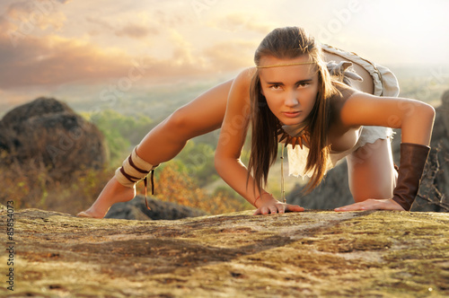 Φωτογραφία Primitive woman on a rock at the sunset. Amazon woman