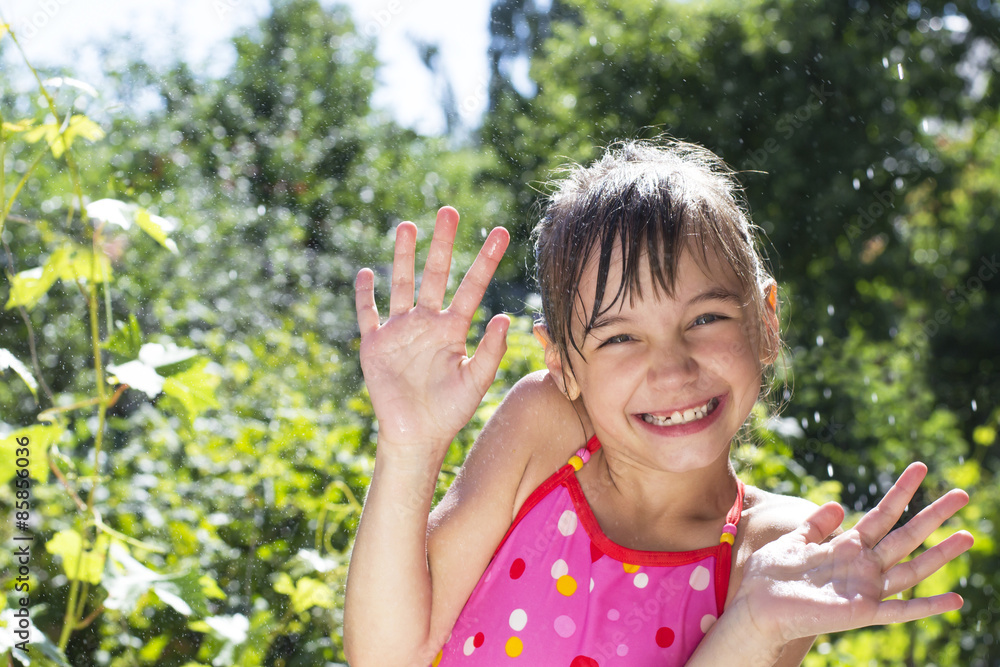 Beautiful little girl in the water spray in the garden Beautiful little girl in the water spray in the garden