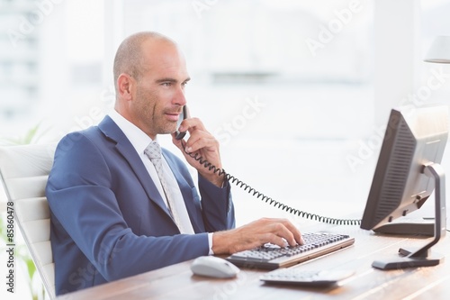 Businessman on the phone and using his computer photo