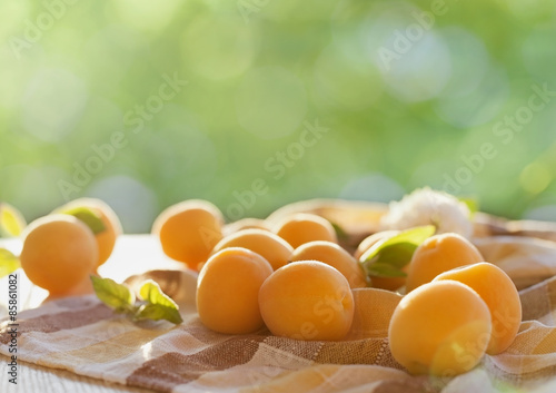 Ripe apricots on wooden table with nature background, selective focus