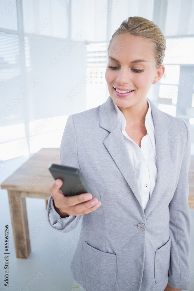 Smiling businesswoman sending a text at her desk Smiling businesswoman sending a text at her desk