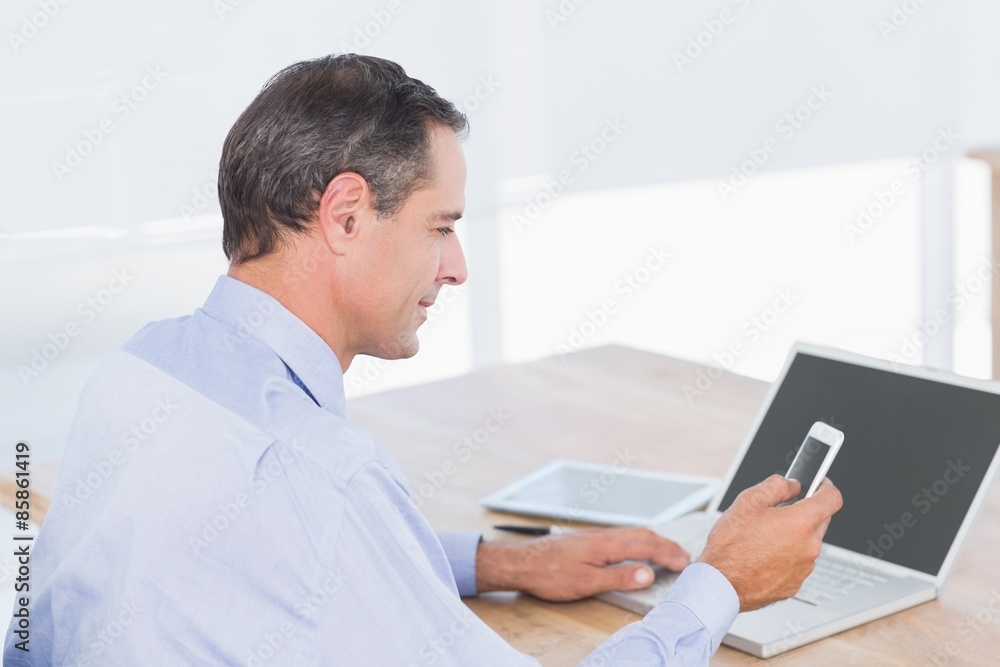 Businessman sending a text at his desk