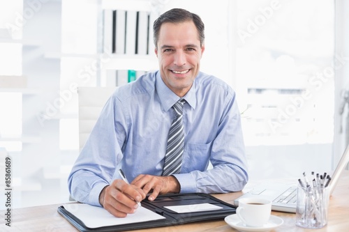 Smiling businessman writing on a paper 