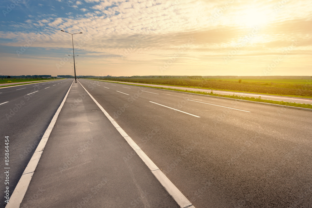 Driving on an empty motorway towards the setting sun