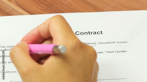 Loan Application - Woman going over a personal loan contract and signs it on the borrower signature line