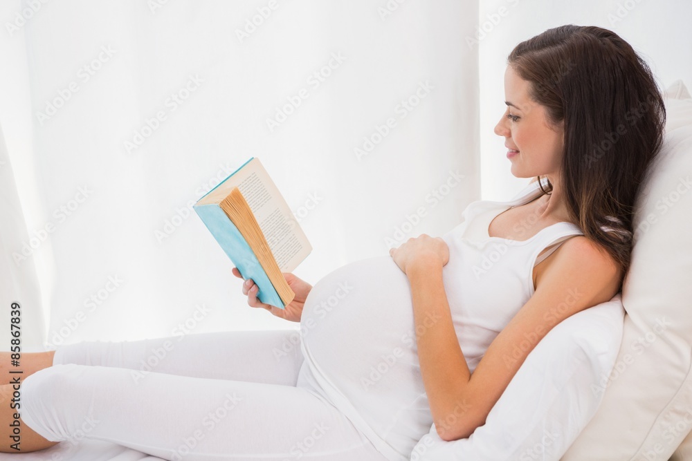 Smiling pregnancy reading in his bed Smiling pregnancy reading in his bed