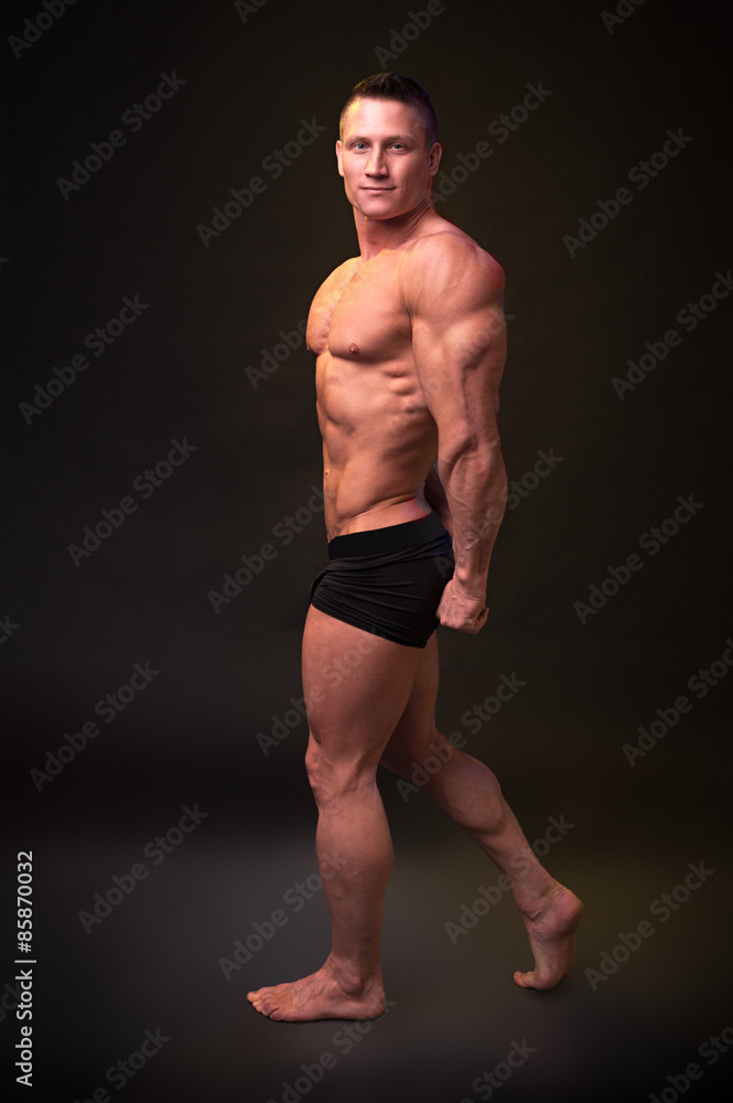 Bodybuilder shows muscles of the triceps on dark background Bodybuilder shows muscles of the triceps on dark background