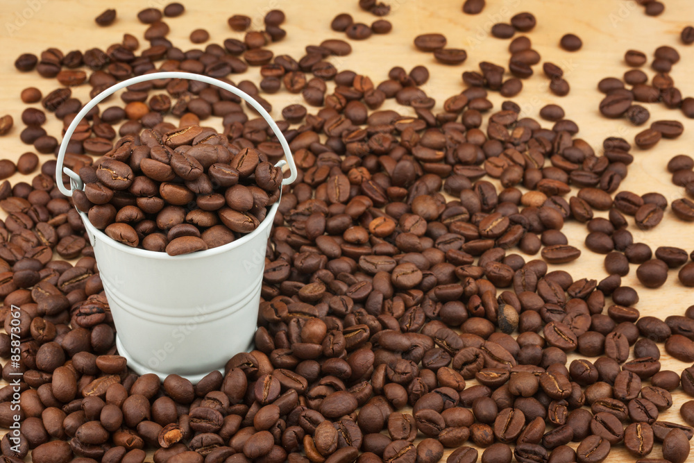 Fototapeta premium White bucket with coffee beans on the wooden floor
