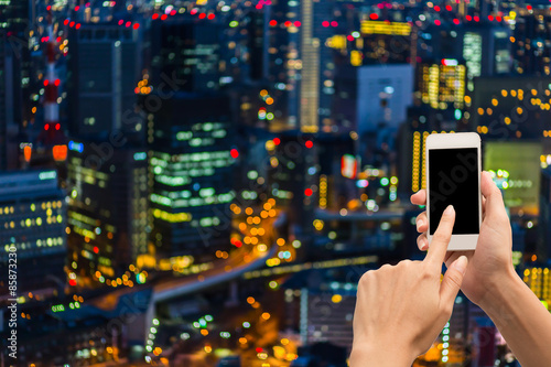Hand using smartphone on bokeh city light background.