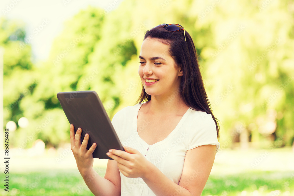 smiling young girl with tablet pc sitting on grass smiling young girl with tablet pc sitting on grass