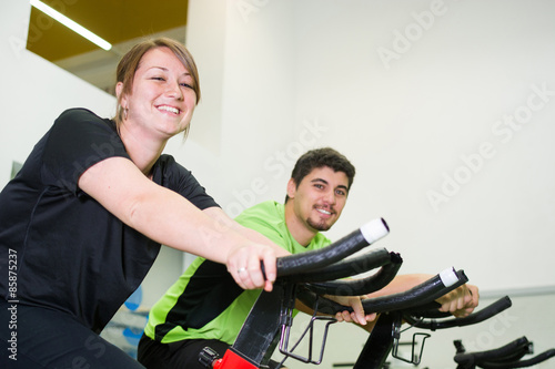 man and woman with stationary bicycle in gym 