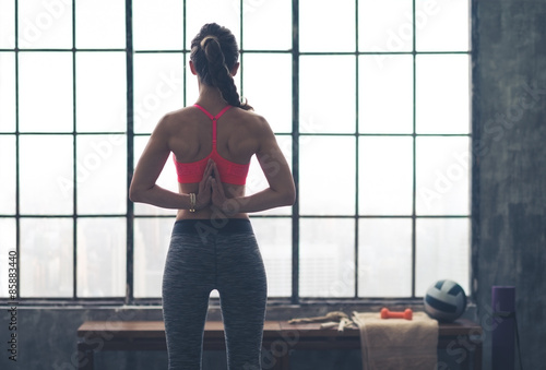 Rear view of woman with hands clasped behind back in yoga pose