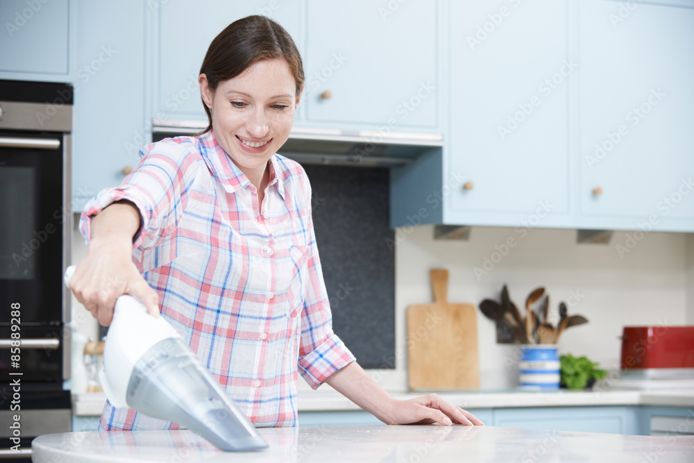 Woman Cleaning Kitchen Using Hand Held Vacuum Cleaner Woman Cleaning Kitchen Using Hand Held Vacuum Cleaner