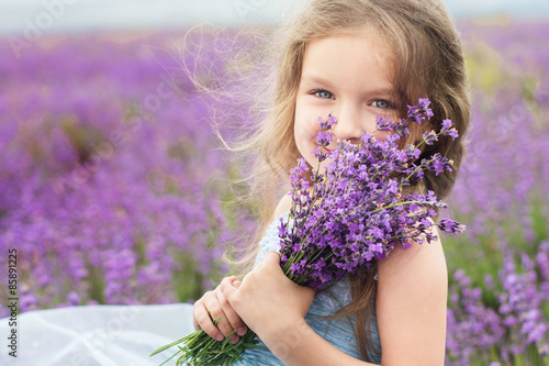 Happy little girl in lavender field with bouquet