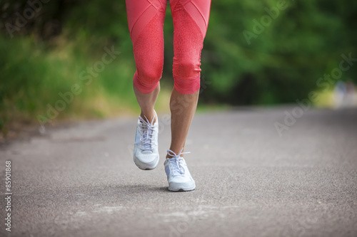 Cropped view of woman athlete running on pathway in park