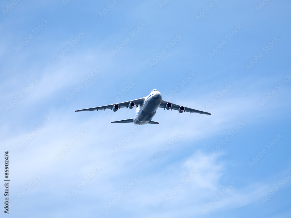 Fototapeta premium Large four engine jet transport aircraft flying high in clear blue sky