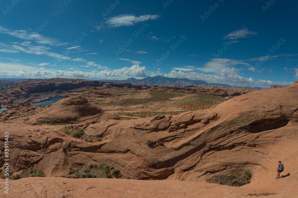 Girl Hiker walking down wavy sandstone towards the lake powell Girl Hiker walking down wavy sandstone towards the lake powell