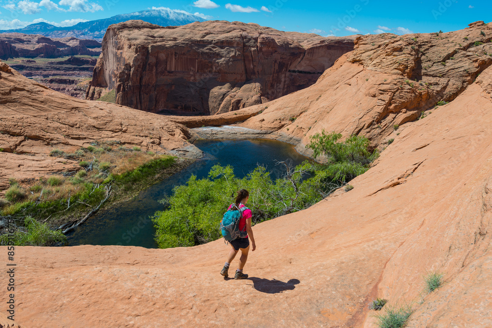 Hiker walking down the slick rock towards small lake