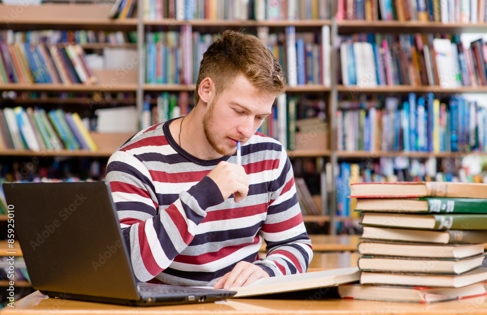 Pensive student with laptop studying in the university library Pensive student with laptop studying in the university library