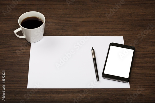 Top view on dark wooden office desk with paper, smartphone with blank screen, pen and cup of coffee.
