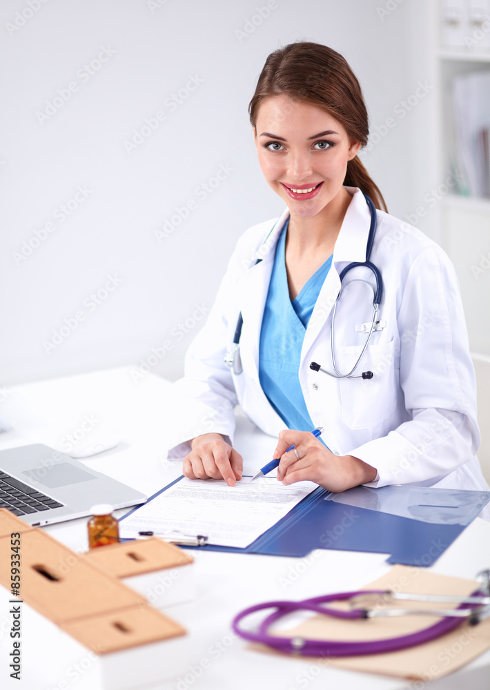 Beautiful young smiling female doctor sitting at the desk and Beautiful young smiling female doctor sitting at the desk and