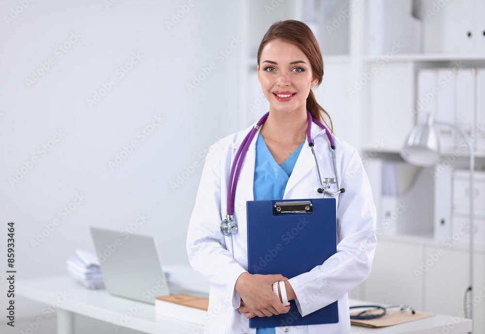 Smiling female doctor with a folder in uniform standing at Smiling female doctor with a folder in uniform standing at