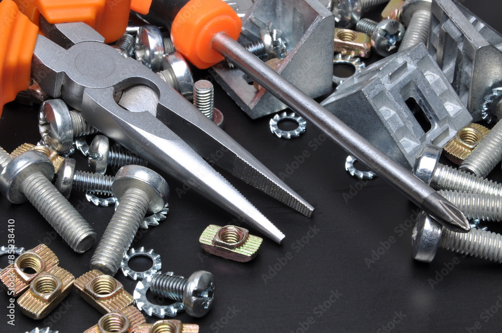 Fototapeta premium Construction tools and bolts on black metal surface 