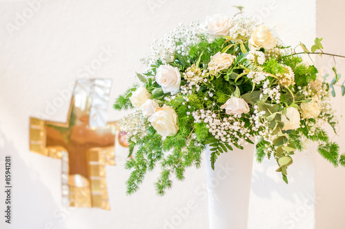 Fototapete A wedding bouquet of white flowers in front of the white altar with a golden cross