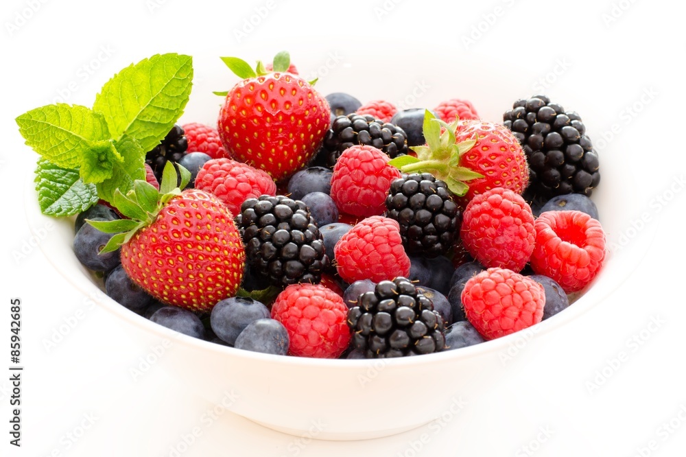 Schüssel mit frischen Beeren (Himbeere, Blaubeere, Brombeere, Erdbeere) und grüner Dekoration Schüssel mit frischen Beeren (Himbeere, Blaubeere, Brombeere, Erdbeere) und grüner Dekoration