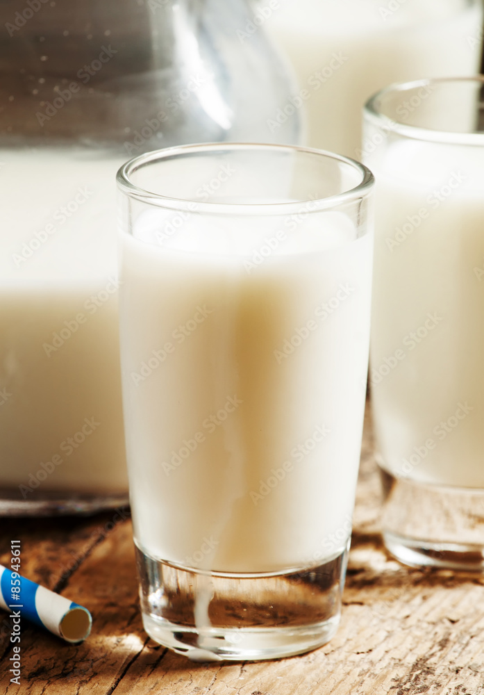 Fresh peasant milk jug and glasses on old wooden table, selectiv Fresh peasant milk jug and glasses on old wooden table, selectiv