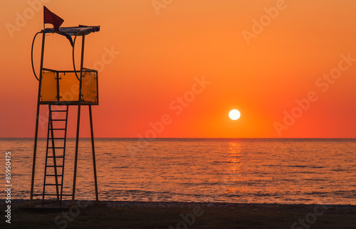 Lifeguard rescue tower on sea beach at sunset