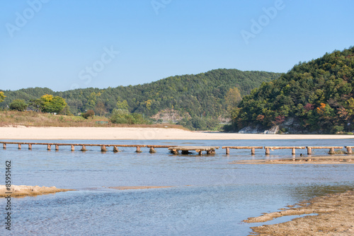 single lane log bridge over a shallow river photo